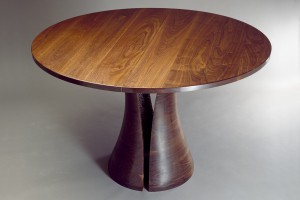 Round walnut dining table with solid carved base expands with leaves by Seth Rolland custom furniture design